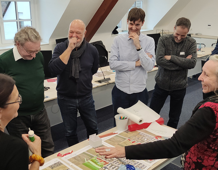 Werkstattgespräch zur Stadtplanung Teilnehmende diskutieren gemeinsam über städtebauliche Planungsunterlagen an einem Tisch