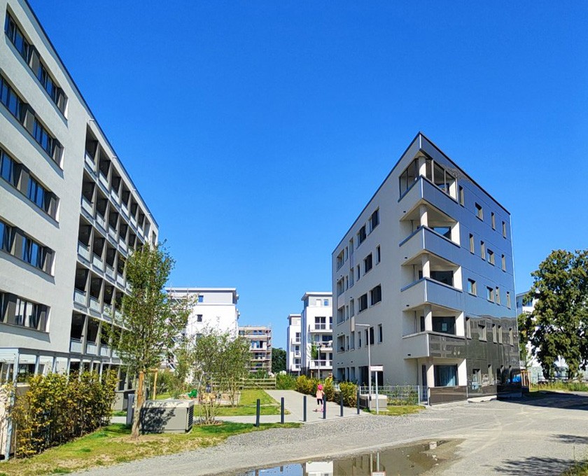 Benjamin-Franklin-Village, Mannheim, 2019 Modernes Wohnquartier mit mehreren mehrstöckigen Gebäuden, Grünflächen und Fußwegen unter klarem blauem Himmel
