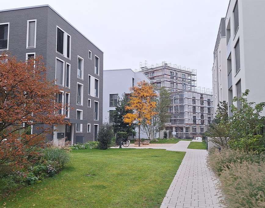 Wohnquartier mit Mehrfamilienhäusern Neues Wohnquartier mit Mehrfamilienhäusern, Grünflächen und einem Gebäude im Bau mit Gerüst